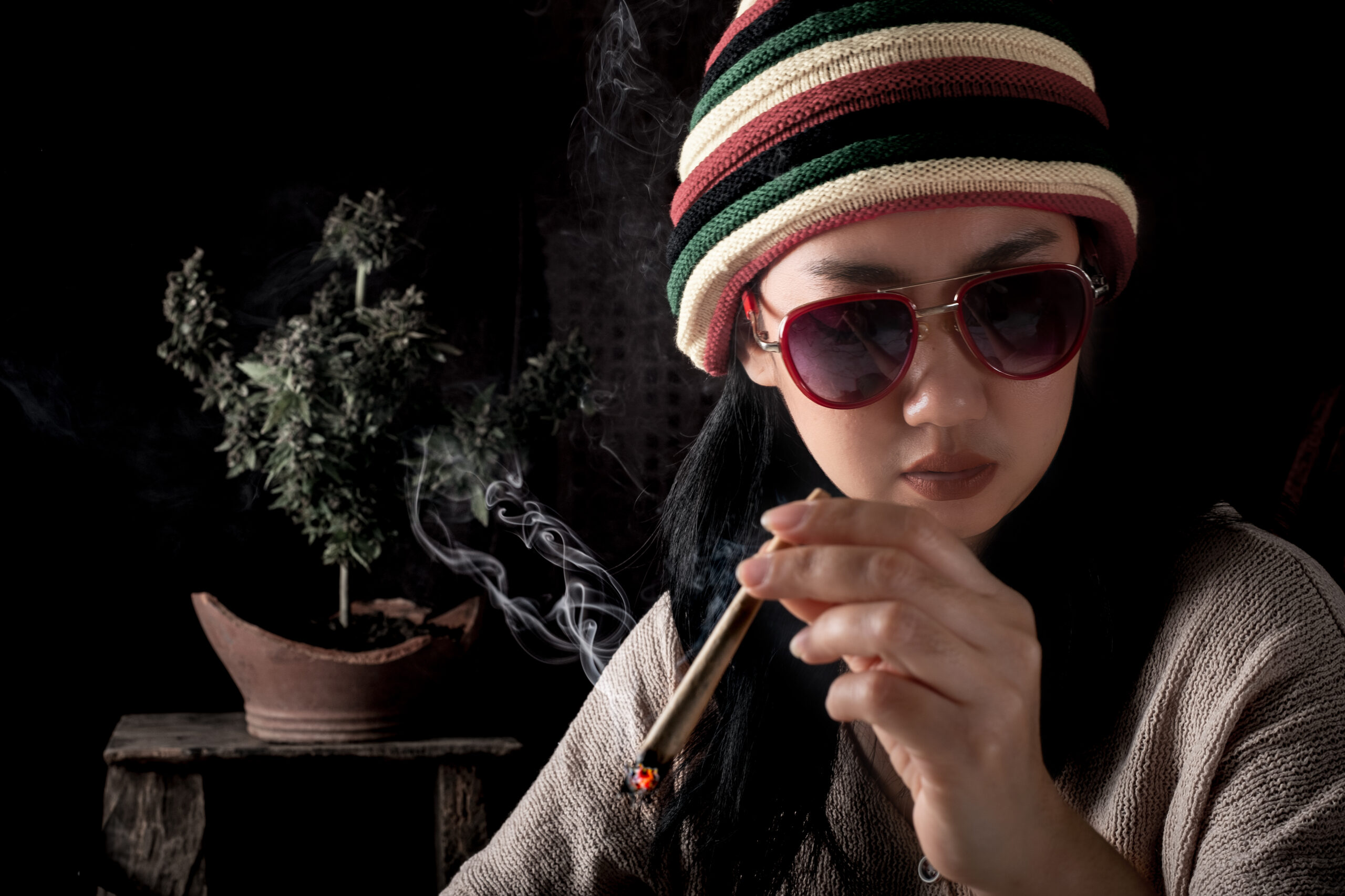 Beautiful Asia women smoking weed at cannabis tree background