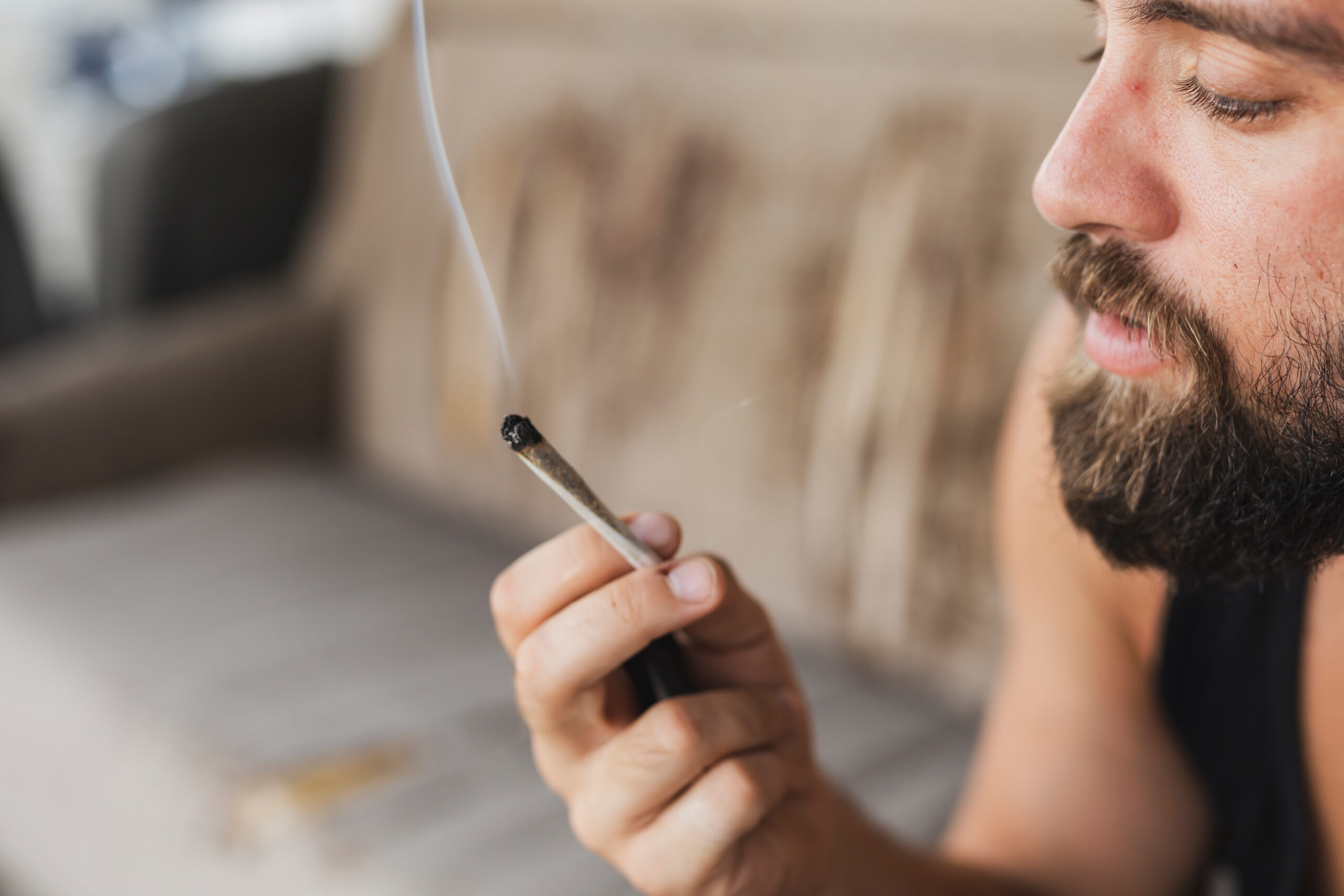 Young man sitting on a couch, relaxing and smoking pot